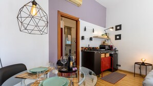A modern living space with a glass dining table, a kitchen area, and a seating area. - Studio 'Il Tuo Rifugio' with Balcony, Wi-Fi and Air Conditioning (Modica)