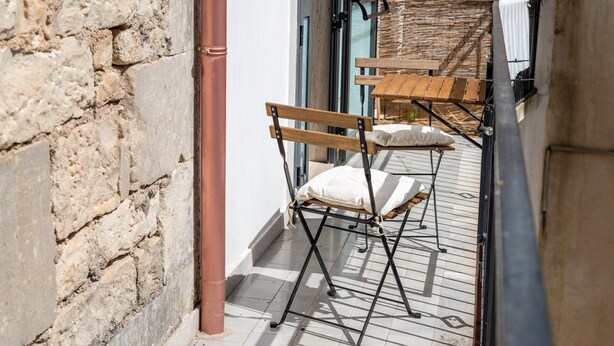 A narrow outdoor corridor with a brick wall, a wooden bench, and a folding table. - Studio 'Il Tuo Rifugio' with Balcony, Wi-Fi and Air Conditioning (Modica)