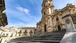 A grand historical building with a prominent bell tower, a staircase leading to the entrance, and classical architectural details. - Studio 'Il Tuo Rifugio' with Balcony, Wi-Fi and Air Conditioning (Modica)