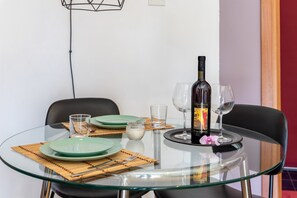 Una mesa de comedor con platos verdes, una botella de vino y copas, sobre posavasos de bambú.