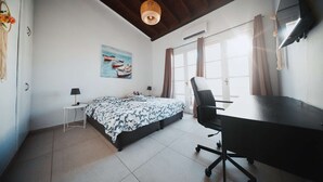 A bedroom with a bed, desk, chair, and a painting of boats. - Lovely 1BR in Old Town: City Center & 4min to Beach (Larnaca)
