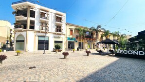 A public square with cobblestone pavement, a building with balconies, and a storefront named 'Nobilia'. - Lovely 1BR in Old Town: City Center & 4min to Beach (Larnaca)