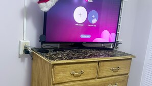 A television on a wooden dresser with a Santa hat on top. - Embassy Visits and Event Stays (Kingston)