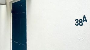 A white exterior wall with a dark door and the number "38A" painted on it. - Embassy Visits and Event Stays (Kingston)