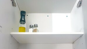 A kitchen with white cabinets, a teal bowl on the counter, a red mug, and a glass with a yellow liquid. - Embassy Visits and Event Stays (Kingston)