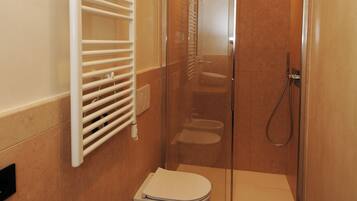 Un bagno con doccia vetrata, un WC bianco e un bidet.
