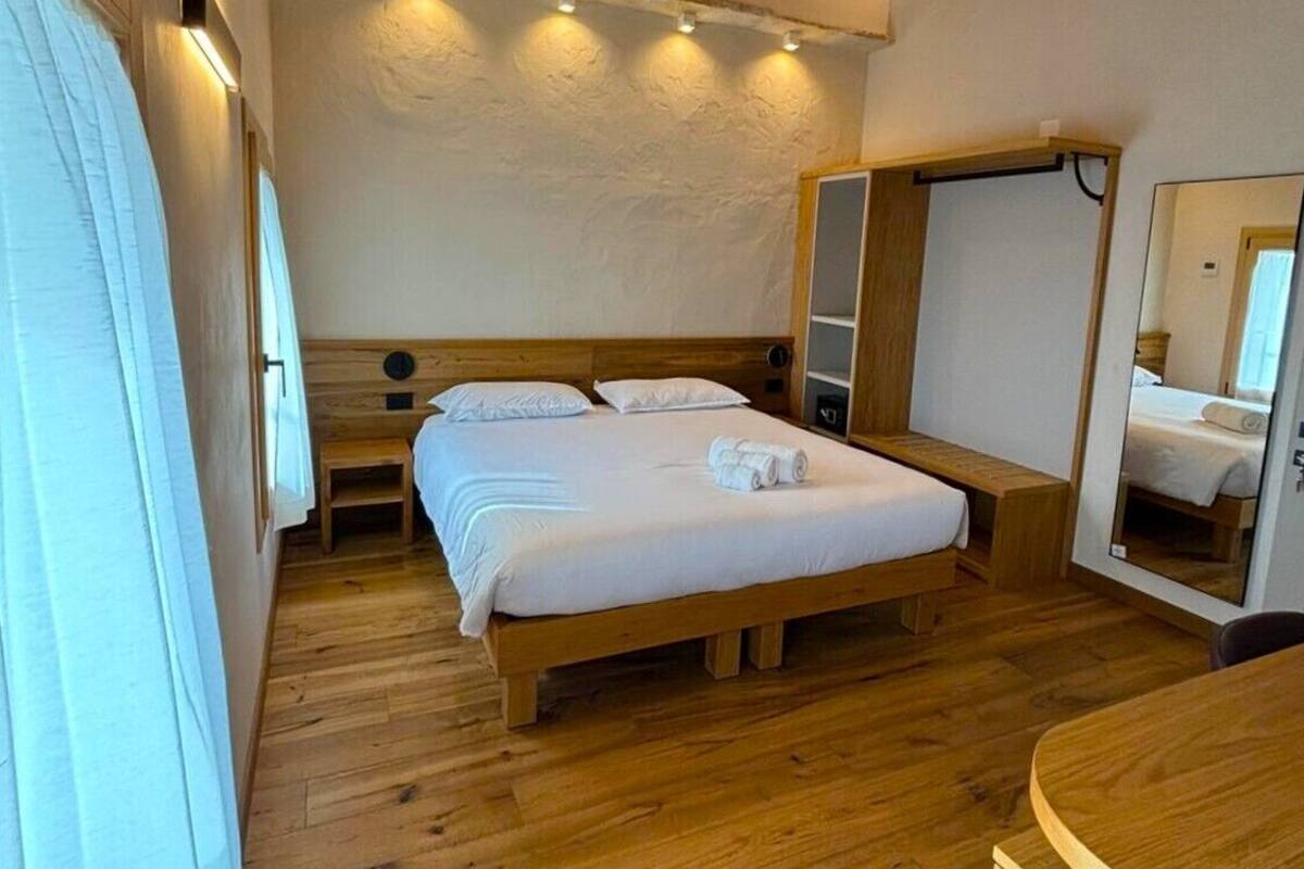 Une chambre à coucher avec un lit en bois, des tables de chevet, un miroir et un plafond en bois.