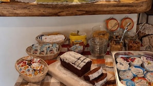 A buffet setup with various food items, including bread, pastries, and beverages.