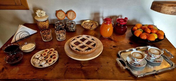 Une table en bois sur laquelle on trouve divers aliments, notamment une tarte, des biscuits et des fruits.