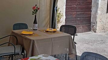 Une table dressée pour deux personnes, avec une bouteille de vin, un vase de fleurs et un menu.