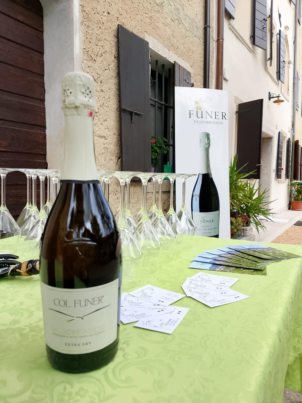 A table with a bottle of Col Funer wine, glasses, and wine cards.
