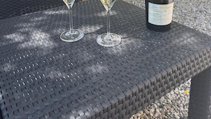 Two wine glasses on a woven table with a bottle of wine.