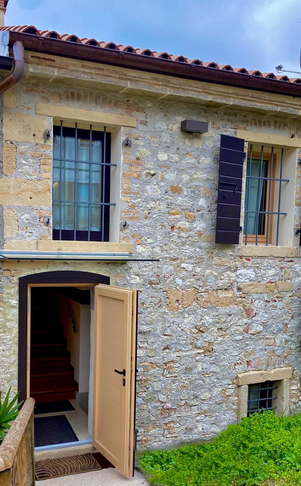 A stone building with a wooden door and a small window with shutters.