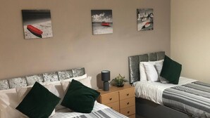 A hotel room with two beds, a nightstand, and three paintings on the wall. - 04 St Andrews - Sleeps 6 (Lytham St. Anne's)