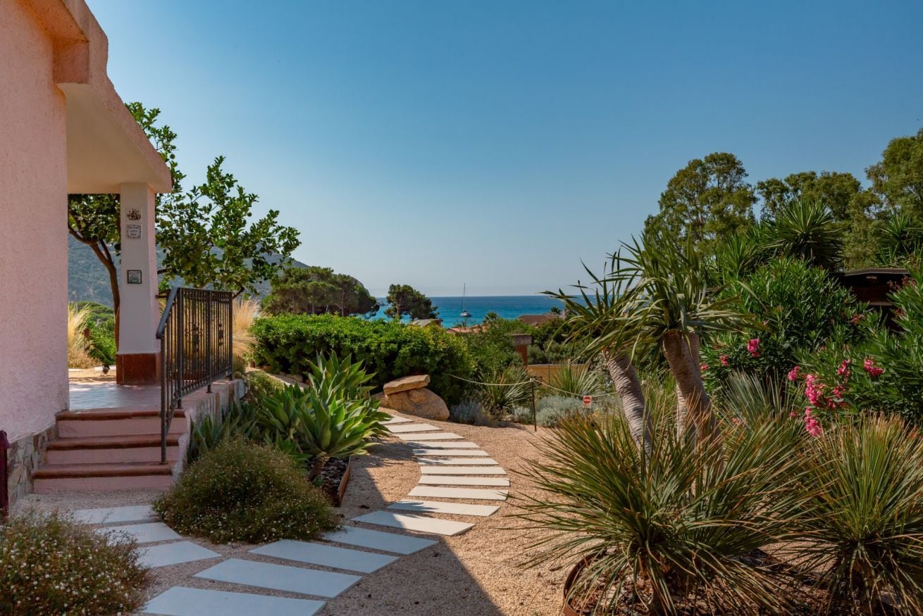 A pathway leading to a building with a view of the sea.