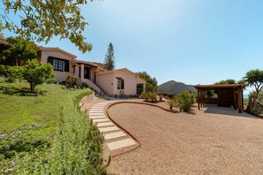 A house with a curved driveway, a pergola, and a mountain in the background.