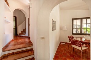 Un escalier menant à une salle à manger avec une table et des chaises, une fenêtre offrant une vue et une décoration murale à motifs.