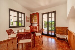 Un coin repas avec une table et des chaises en bois, un buffet et de grandes fenêtres.