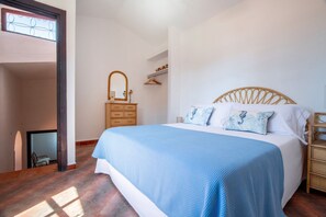 A bedroom with a large bed, a dresser, a mirror, and a wardrobe.