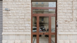 A building entrance with a stone facade and a wooden double door.