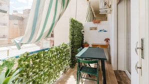 A balcony with a table and chairs, a potted plant, and a striped curtain.