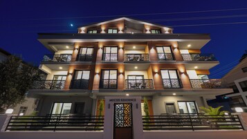 Un edificio de varios pisos con balcones, una entrada con reja y un letrero que dice 'MUCIZE RESIDENCE'.