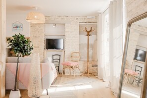Una habitación acogedora con televisión, planta, silla de mimbre y espejo.