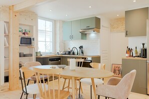 A modern kitchen with a dining area, featuring a round table, chairs, and built-in appliances.