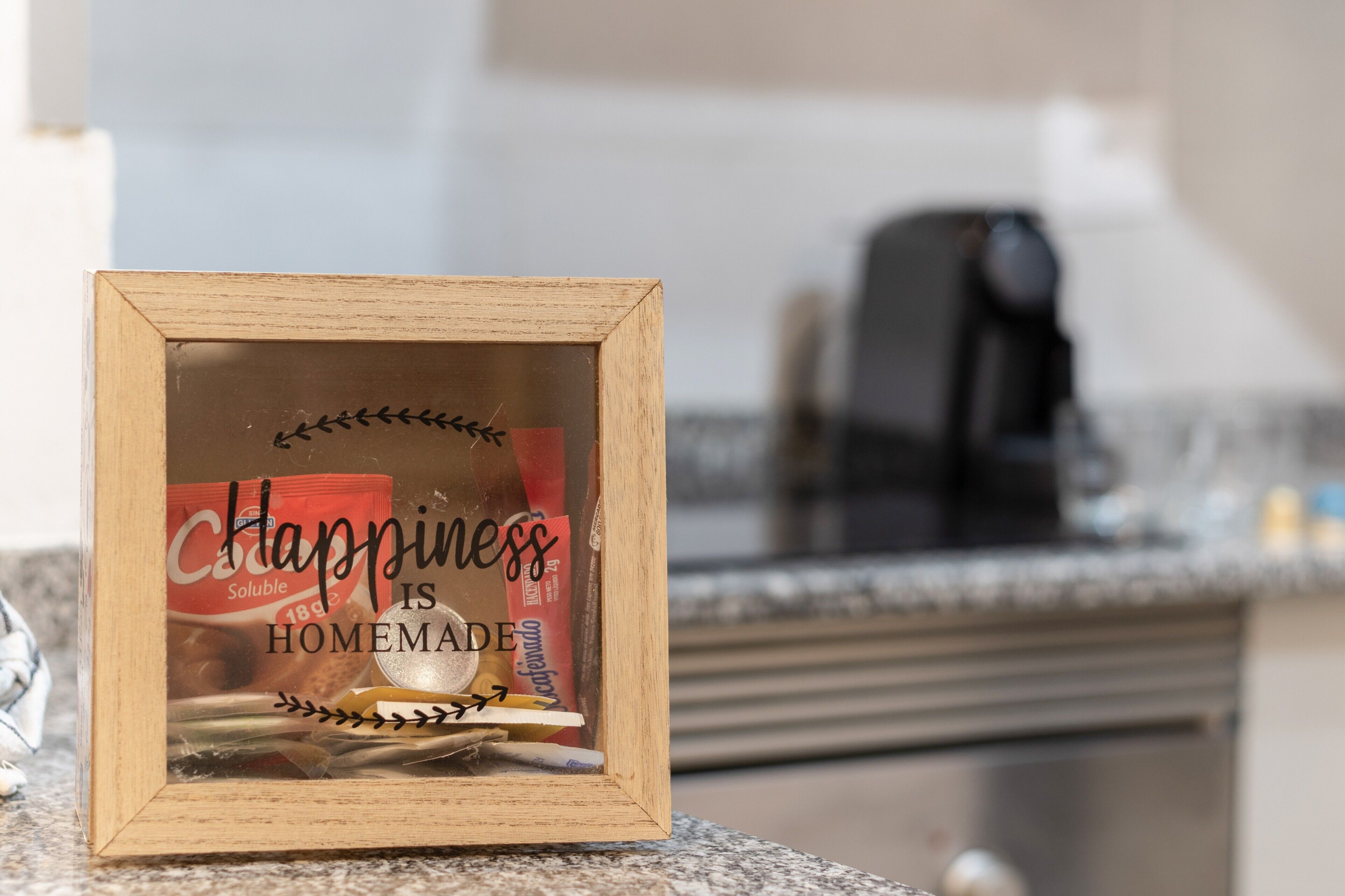 A framed sign with the text 'Happiness is Homemade' on a kitchen counter.