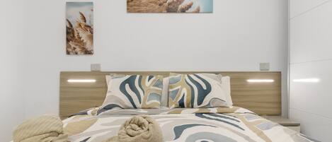 A modern hotel room with a bed, a headboard, and two wall-mounted artworks.