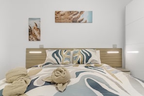 A modern hotel room with a bed, a headboard, and two wall-mounted artworks.