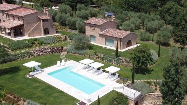 Un'ampia casa circondata da vegetazione lussureggiante e un giardino curato, con piscina.