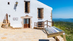 A white building with stone accents, a wooden door, and a stone staircase leading to a balcony. - La Rosa de los Vientos – Charming Stay with Sea Views for Peaceful Days (La Serratella)