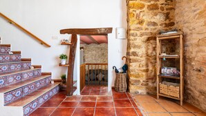 A staircase with patterned tiles, a wooden handrail, a stone wall, and a shelf with items. - La Rosa de los Vientos – Charming Stay with Sea Views for Peaceful Days (La Serratella)