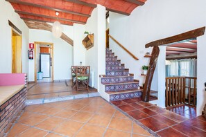 A spacious hallway with a staircase, a fire extinguisher, and a seating area.