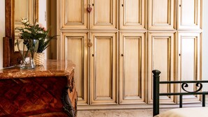 A room with a wooden dresser, a bed with a black headboard, and a large wardrobe with multiple doors. - Apartment 'Anita' with Sea View, Private Terrace and Wi-Fi (Capoliveri)