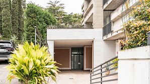 A building entrance with a gated driveway, a potted plant, and a staircase leading to a balcony.