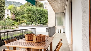 A wooden table with wicker baskets on a balcony with a view of greenery and buildings.
