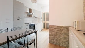 Een moderne keuken met witte kasten, een eettafel met stoelen en een hanglamp.