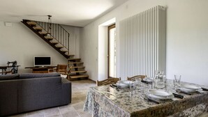 Un coin repas avec une table dressée pour quatre personnes, un canapé, un escalier et un radiateur.