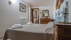 A bedroom with a bed, a dresser, a mirror, and a radiator.