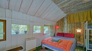 Ein gemütliches Zimmer mit Bett, Fenstern, einer Bank und einer Heizung.