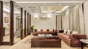 A modern living room with a sectional sofa, a coffee table, and a ceiling fan. - Geet by Akama Homes (New Delhi)