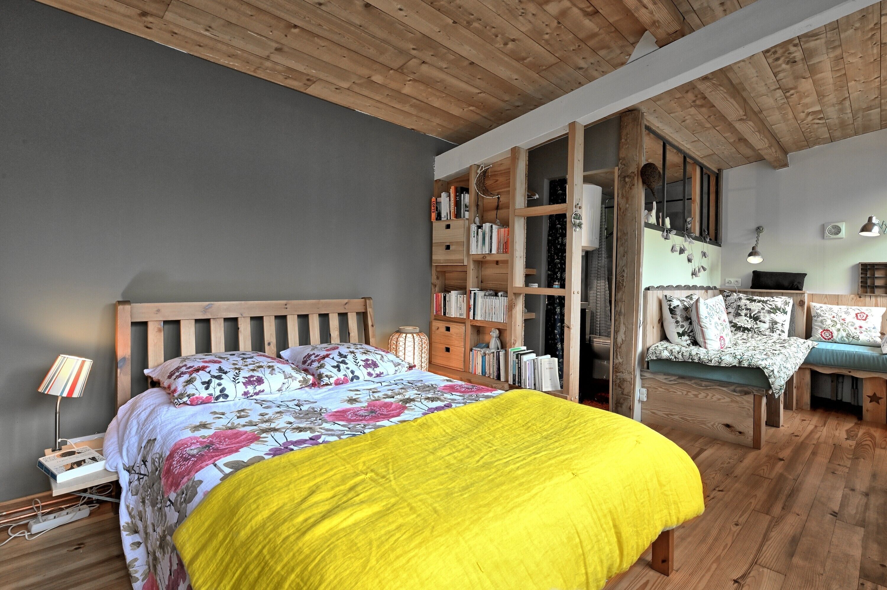 A bedroom with a wooden bed, a bookshelf, a chair, and a desk.