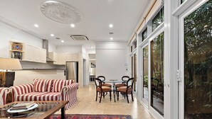 A modern kitchen with white cabinets, a striped sofa, and a dining area with a table and chairs.