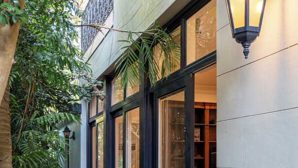 A building with large glass doors, a black metal lantern, and a brick pathway.