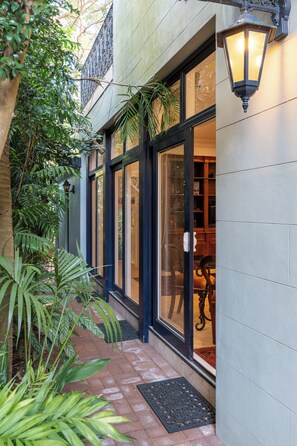 A building with large glass doors, a black metal lantern, and a brick pathway.