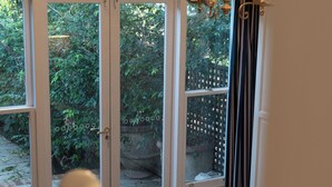 A bedroom with a large window, a chandelier, and a view of greenery outside.