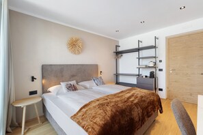 Une chambre moderne avec un lit, une table de chevet, des étagères murales et une porte en bois.