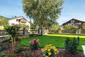 Un quartier résidentiel comprenant deux maisons, une pelouse bien entretenue et une variété de plantes à fleurs.